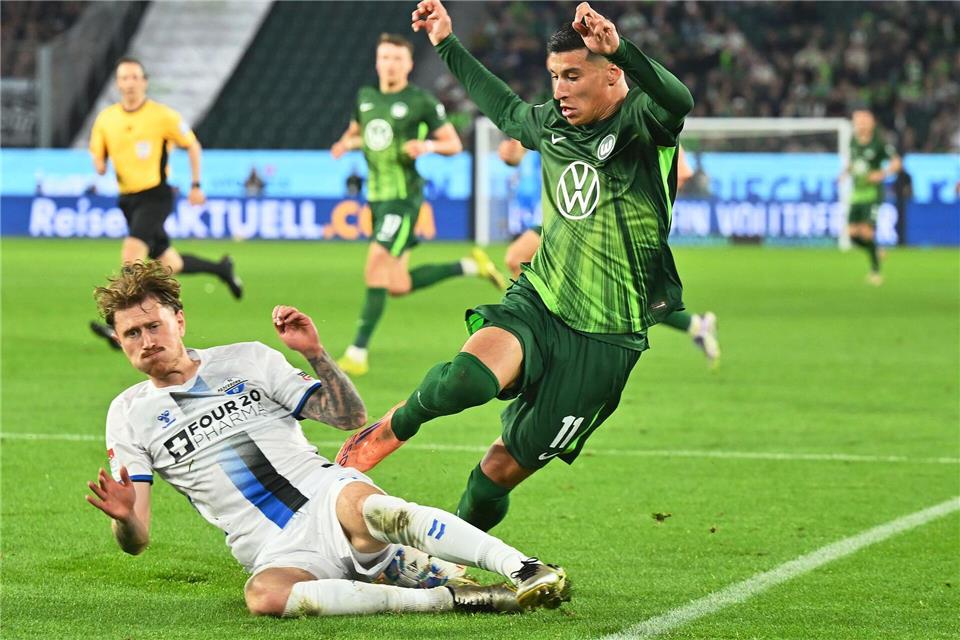 Hartnäckiger Außenseiter: Paderborns Calvin Brackelmann (l) stoppt den Wolfsburger Adam Daghim im Relegations-Hinspiel.Swen Pförtner/dpa