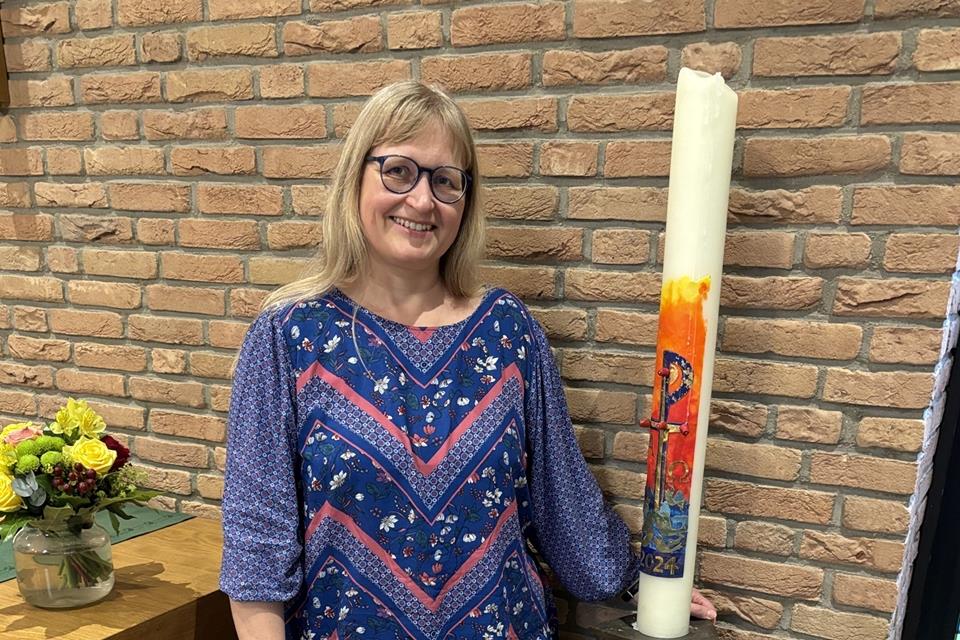 Heidi Bergmann steht neben der Kerze, die die evangelische Gemeinde traditionell von katholischen Christen geschenkt bekommt.