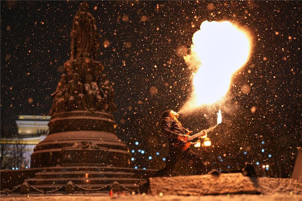 Heiß und kalt: Ein Straßenkünstler führt bei Schneefall eine Feuershow im russischen St. Petersburg auf.Dmitri Lovetsky/AP/dpa
