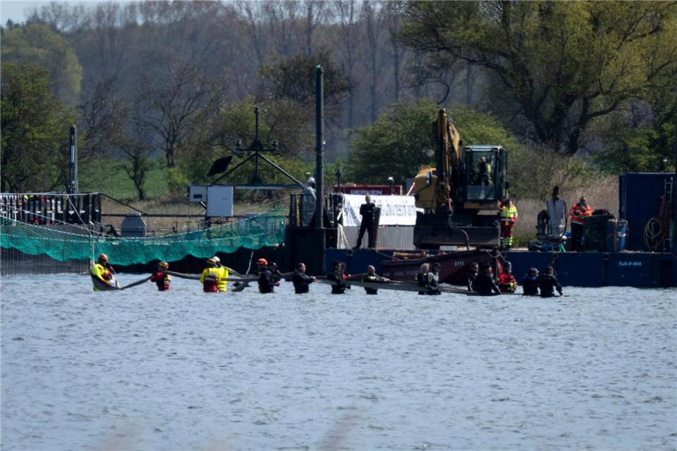 Helfer versuchen den gestrandeten Wal aus dem flachen Wasser zu einem Transportschiff zu ziehen, das in der Fahrrinne wartet.Philip Dulian/dpa