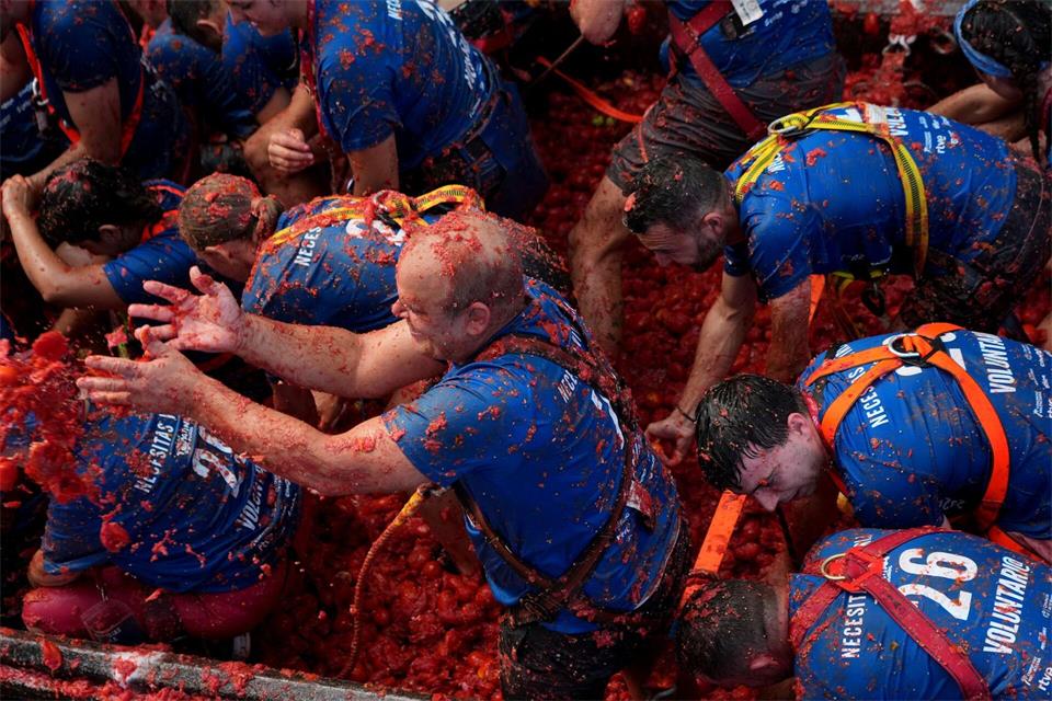 Helfer werfen die überreifen und weichen Tomaten von langsam durch die Innenstadt fahrenden Lastwagen in die Menschenmenge. Danach kippen die Lastwagen den Rest der rund 150 Tonnen roter Früchte ab und die Teilnehmer der „La Tomatina“ stürzen sich darauf, um sich mit neuen Wurfgeschossen zu versorgen. Alberto Saiz/AP/dpa