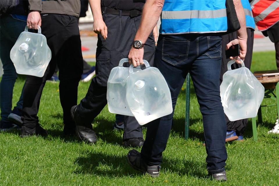 Helferinnen und Helfer tragen Wassercontainer an Tische an der Sammelstelle am Altona Balkon.Marcus Brandt/dpa