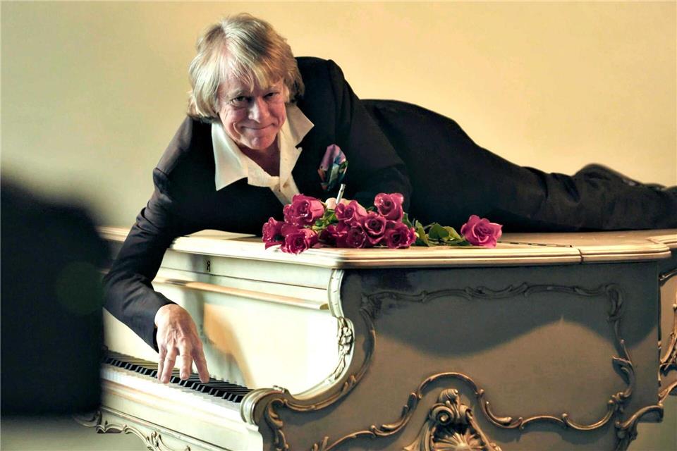 Helge Schneider liegt auf einem Klavier in einer Szene des Films „Helge Schneider - The Klimperclown“, der nun in der Mediathek zu sehen ist und am Mittwoch, 20.8., im Ersten gezeigt wird.-/SWR Presse/Bildkommunikation/dpa