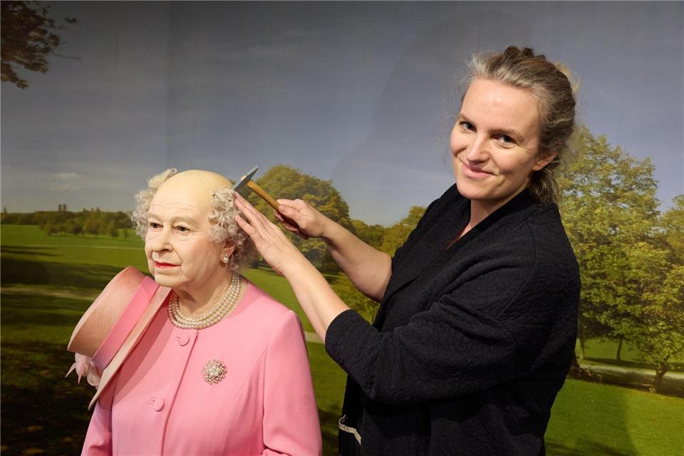 Henriette Masmeier, Maskenbildnerin, montiert mit Hammer und Nagel die Haare der Wachsfigur von Queen Elisabeth II.Georg Wendt/dpa