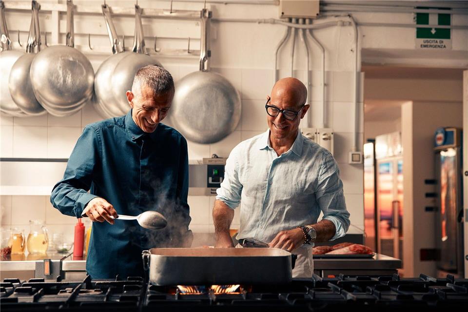 Hier lässt sich der Schauspieler Stanley Tucci (rechts) von Giuseppe Bertoleoni auf der Insel Tavolara vor Sardinien bekochen. Tucci besucht in der 2. Staffel von „Stanley Tucci in Italien“ wieder viele Küchen.Matt Holyoak/National Geographic/dpa