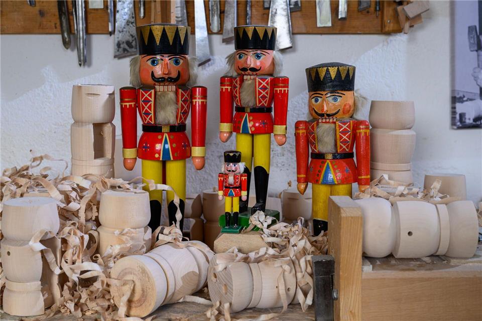 Historische Nussknacker und der Mini-Nussknacker „Willhelm“, der 2021 auf der Internationalen Raumstation ISS zu Gast war, stehen in der Werkstatt von Holzspielzeugmacher Markus Füchtner in Seiffen. Hendrik Schmidt/dpa