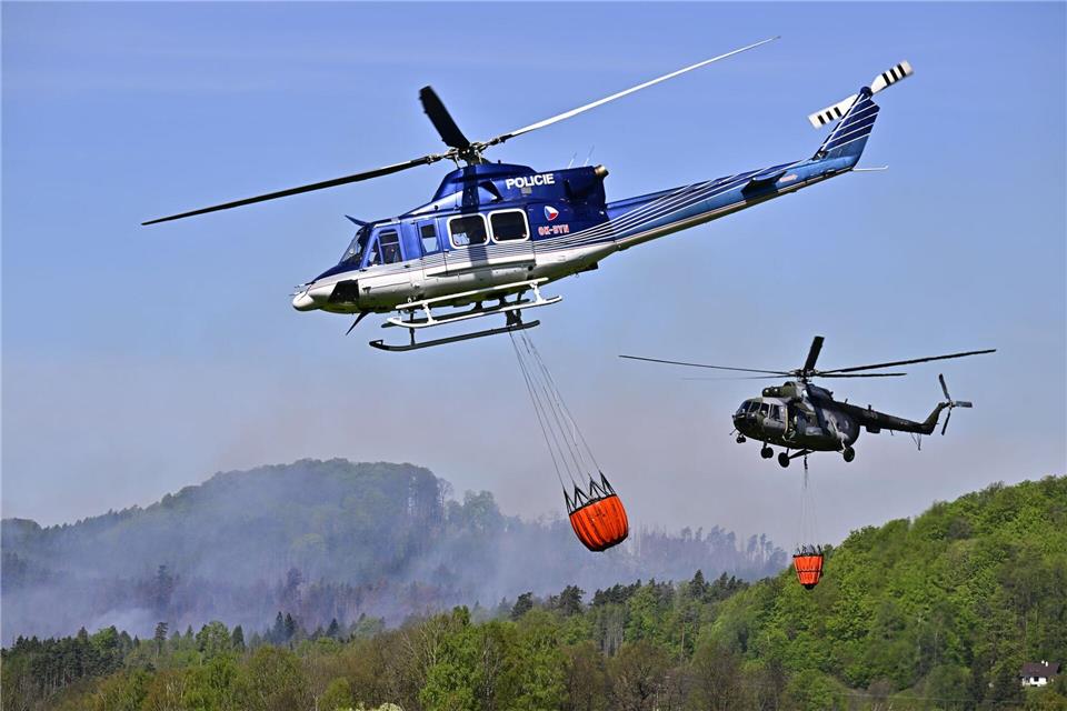 Hubschrauber fliegen mit Löschwasser-Behältern zu einem Waldbrand im Nationalpark Böhmische Schweiz.Hájek Ondøej/CTK/dpa
