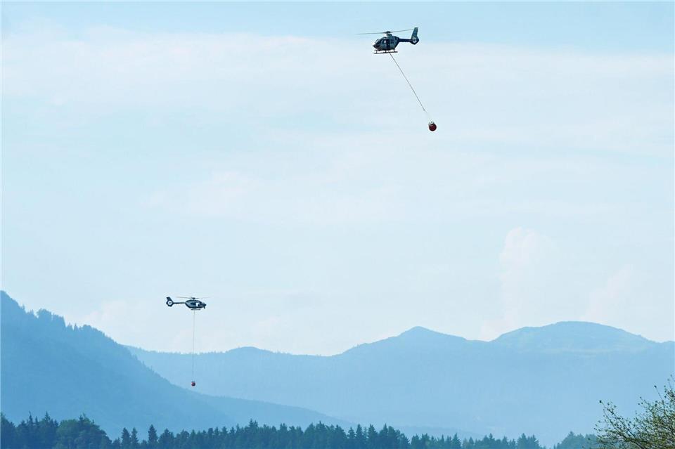 Hubschrauber mit Löschwasser aus dem Chiemsee fliegen zu einem Wald- und Moorbrand. (Archivbild)Uwe Lein/dpa