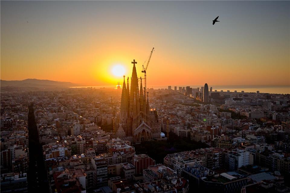 Im Gegenlicht der aufgehenden Sonne ist das Kreuz aus Deutschland auf der Spitze des höchsten Turms der Basilika Sagrada Família in Barcelona gut zu erkennen. (Archivbild)Emilio Morenatti/AP/dpa