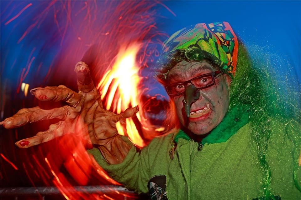 Hexen und Teufel feiern Walpurgisnacht im Harz Im Hexenkostüm steht ein Besucher des Walpurgisfestes in Schierke am Feuer.