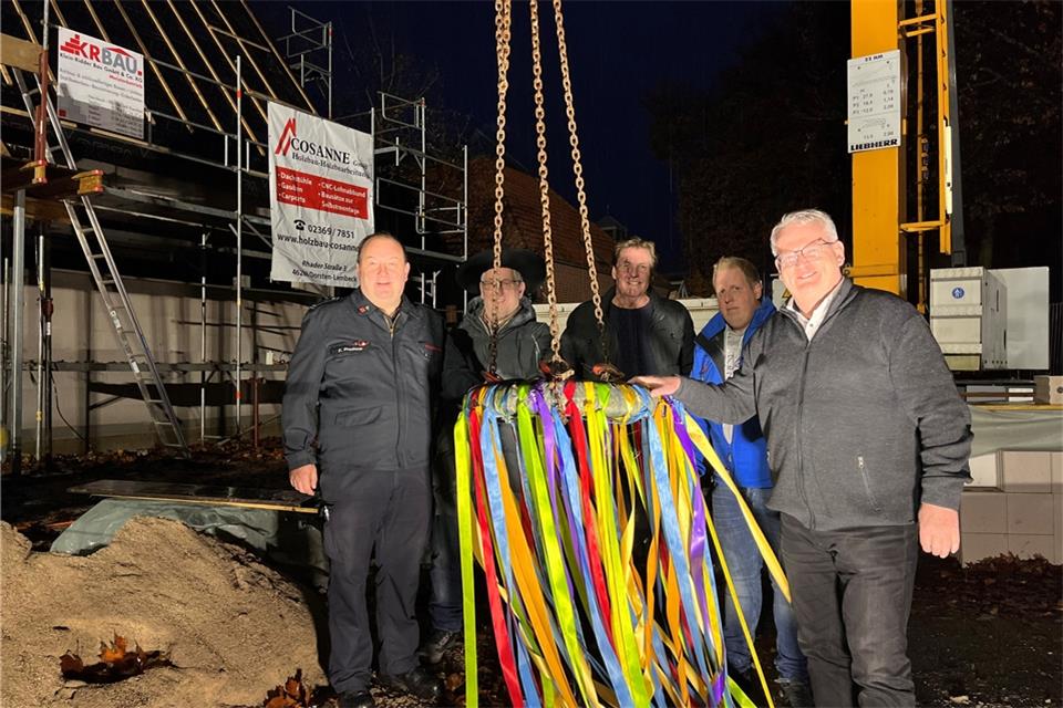 Im Licht der Scheinwerfer, die die Feuerwehr sonst für Einsätze benutzt, wurde der Richtkranz am Kran befestigt (von links): Löschzugleiter Frank Prochnow, Bernhard Cosanne, Alfons Klein-Ridder, Simon Klein-Ridder und Martin Tesing.