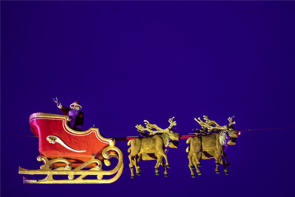 In 30 Metern Höhe fliegt der Weihnachtsmann mit seinem Schlitten über den Weihnachtsmarkt in Bochum. Christoph Reichwein/dpa