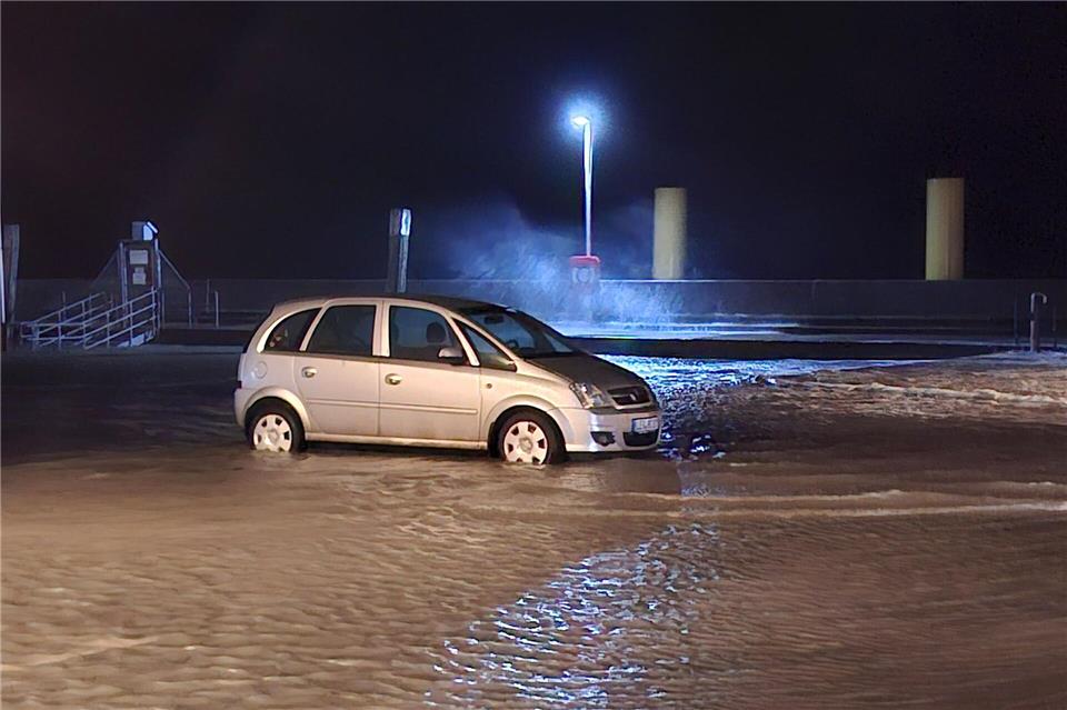 Sturmtief über Deutschland – Bäume stürzen um In Wilhelmshaven steht ein Auto auf einem überfluteten Parkplatz. Kai Moorschlatt/dpa