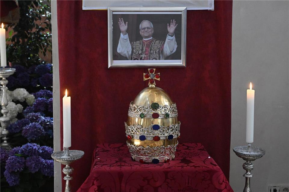 Münchner Petrusfigur erhält nach der Papstwahl Tiara zurück In der Münchner Stadtpfarrkirche ist die Tiara der Petrusfigur vor einem Bild des neuen Papstes Leo XIV. zu sehen.Felix Hörhager/dpa