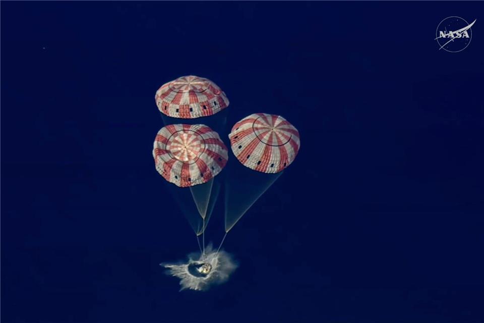 In diesem Bild aus einem von der NASA zur Verfügung gestellten Video taucht die „Artemis 2“ Orion-Kapsel in den Pazifischen Ozean ein.NASA/AP/dpa