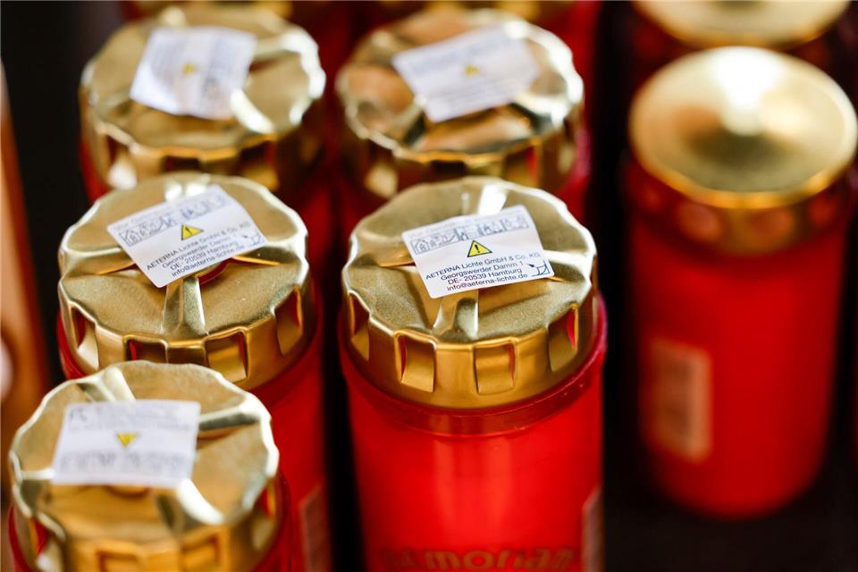 In einer Friedhofsgärtnerei stehen Grablichter zum Verkauf in einem Regal. Thomas Banneyer/dpa