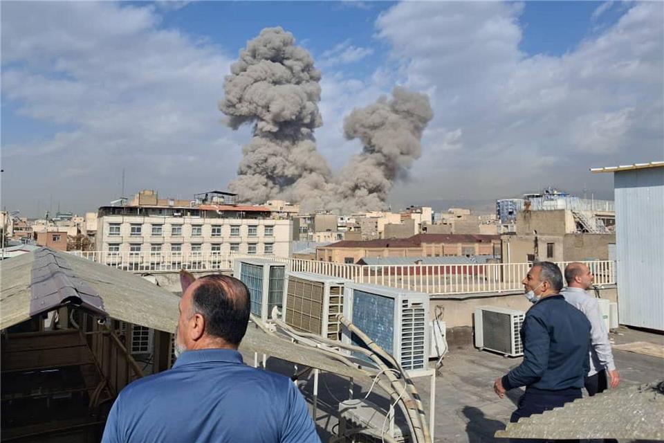 Israel greift den Iran an - Menschen beobachten Rauch nach einer Explosion in Teheran.Uncredited/AP/dpa