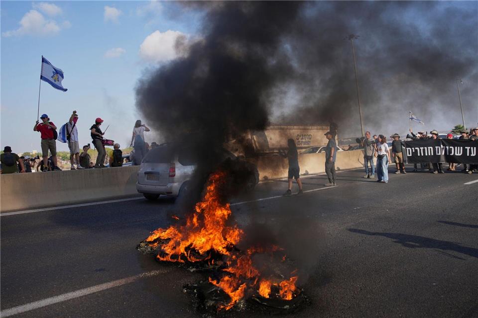 Israelische Demonstranten blockieren eine Straße bei einem Protest.Ohad Zwigenberg/AP/dpa