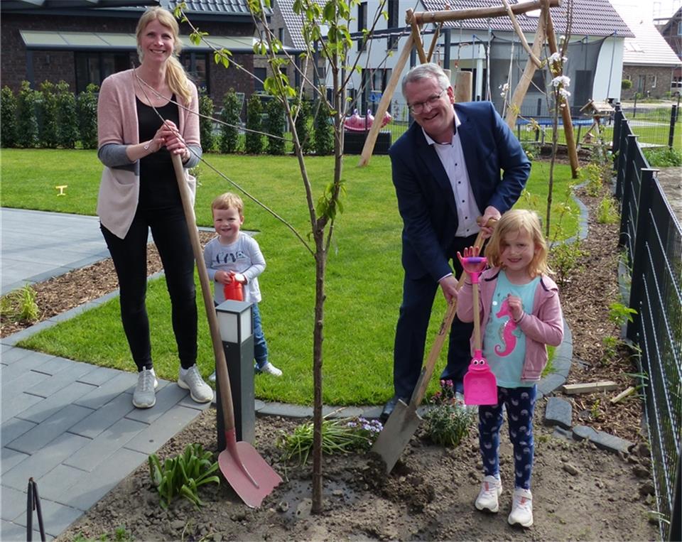 Jacqueline, Felix und Sophie Knufmann freuen sich mit Bürgermeister Martin Tesing, über den frisch eingepflanzten Kirschbaum.