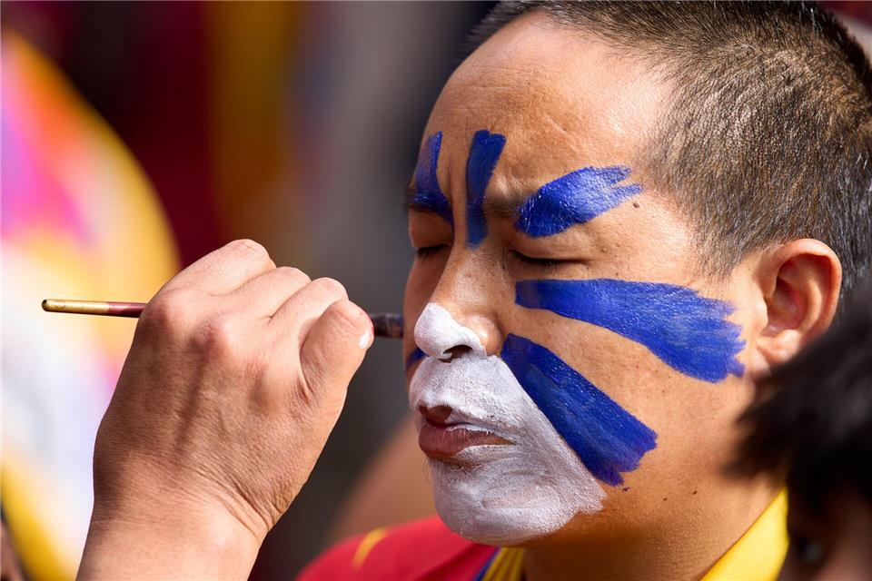 Jahrestag des Aufstandes gegen die chinesische Besatzung in Tibet: Ein tibetischer Mönch im Exil lässt sein Gesicht in einem Tempel in Indien in den tibetischen Farben bemalen.Ashwini Bhatia/AP/dpa