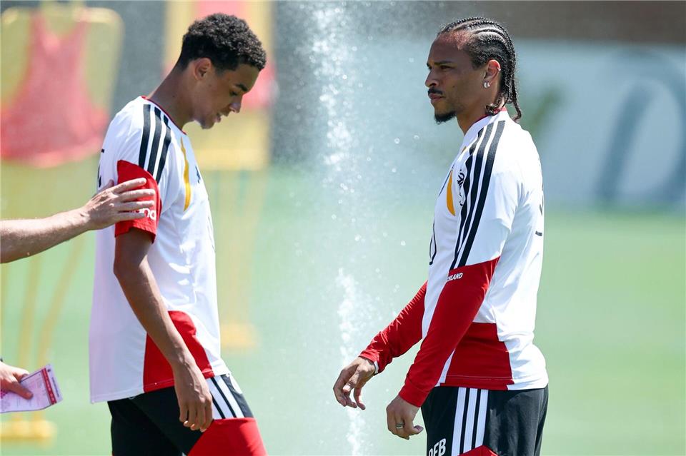 Jamal Musiala und Leroy Sané freuen sich über den Wassersprenger. Christian Charisius/dpa