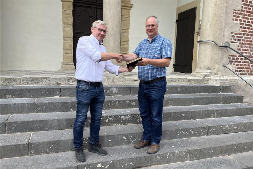 Johannes Bonhoff (l.) übergibt das historische Buch vor der Kapelle an den neuen Bürgermeister der Freiheit, Hermann-Josef Küpers.