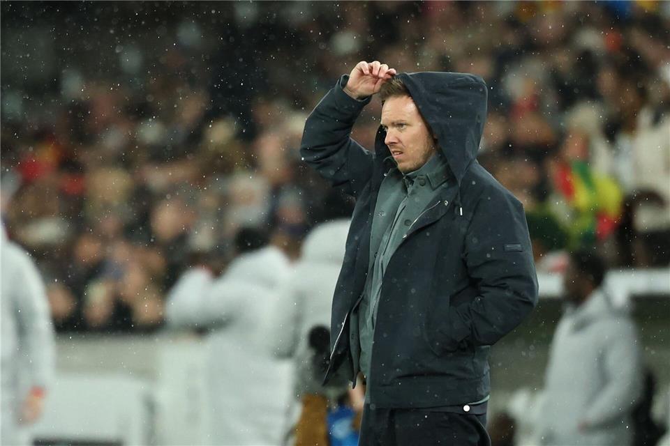 Julian Nagelsmann zieht sich im Regen eine Kapuze über den Kopf.Christian Charisius/dpa
