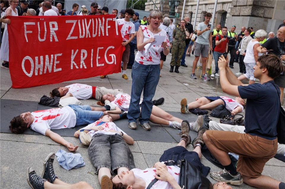 Junge Menschen protestieren beim Veteranentag gegen die Wehrpflicht während des Auftritts von Verteidigungsminister Pistorius. Carsten Koall/dpa