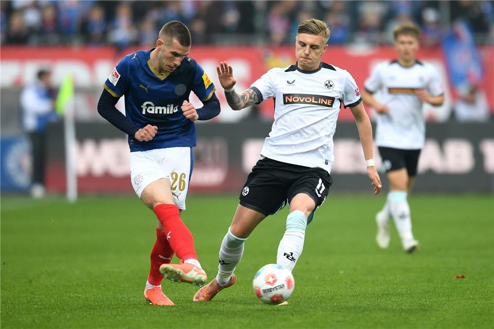 Kaiserslauterns Norman Bassette (r) stört den Kieler Torschützen David Zec.Daniel Bockwoldt/dpa