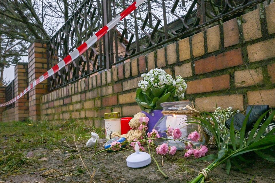 Kerzen und Blumen liegen vor einem Haus in Berlin-Mahlsdorf, in dem nach einem Feuer ein Kind gestorben ist.Jens Kalaene/dpa