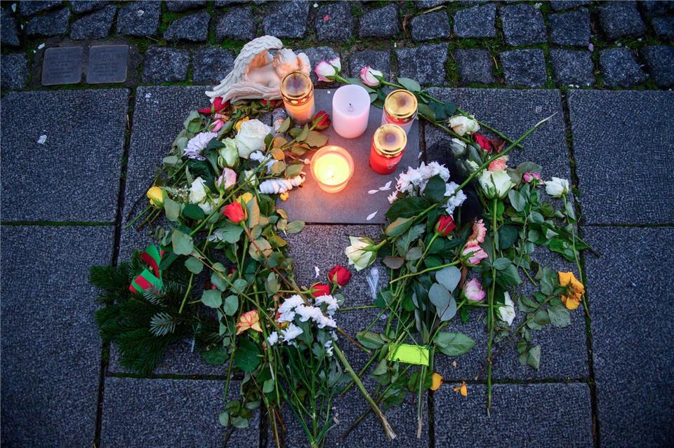 Kerzen und Blumen umgeben eine Gedenkplatte im Gehweg, die an ein Opfer des Anschlags auf den Magdeburger Weihnachtsmarkt erinnert.Klaus-Dietmar Gabbert/dpa