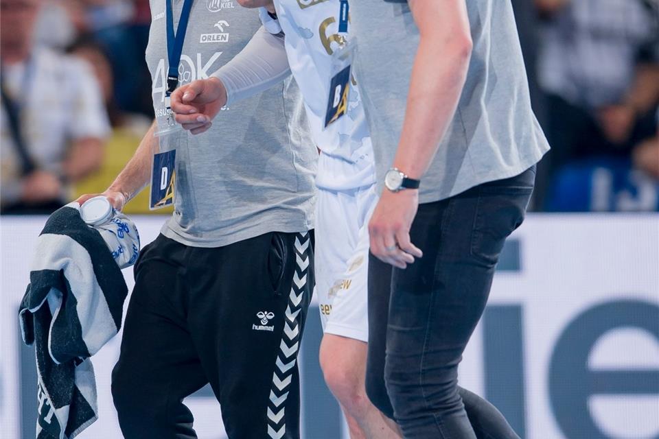 Kiels Hendrik Pekeler (M) wird verletzt vom Platz geführt.