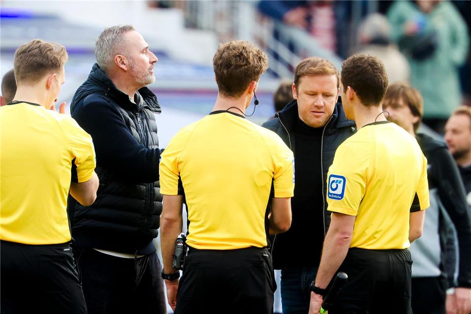 Kiels Trainer Tim Walter (2.v.l.) und Kiels Geschäftsführer Sport Olaf Rebbe (2.v.r.) unterhalten sich mit dem Schiedsrichtergespann.Frank Molter/dpa