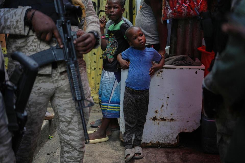 Kind neben bewaffnetem Polizisten in Unterkunft für Vertriebene in Port-au-PrinceOdelyn Joseph/AP/dpa