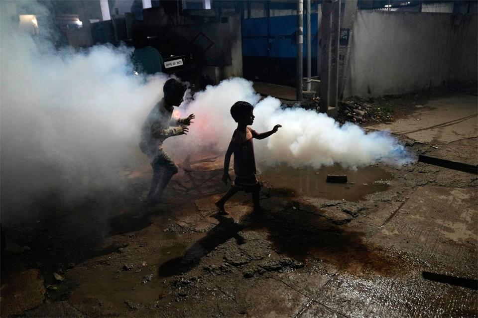 Kinder spielen inmitten der Dämpfe, die entstehen, als ein Mitarbeiter der Stadtverwaltung von Hyderabad ein Wohngebiet ausräuchert, um die Ausbreitung von durch Mücken übertragenen Krankheiten zu verhindern.Mahesh Kumar A./AP/dpa