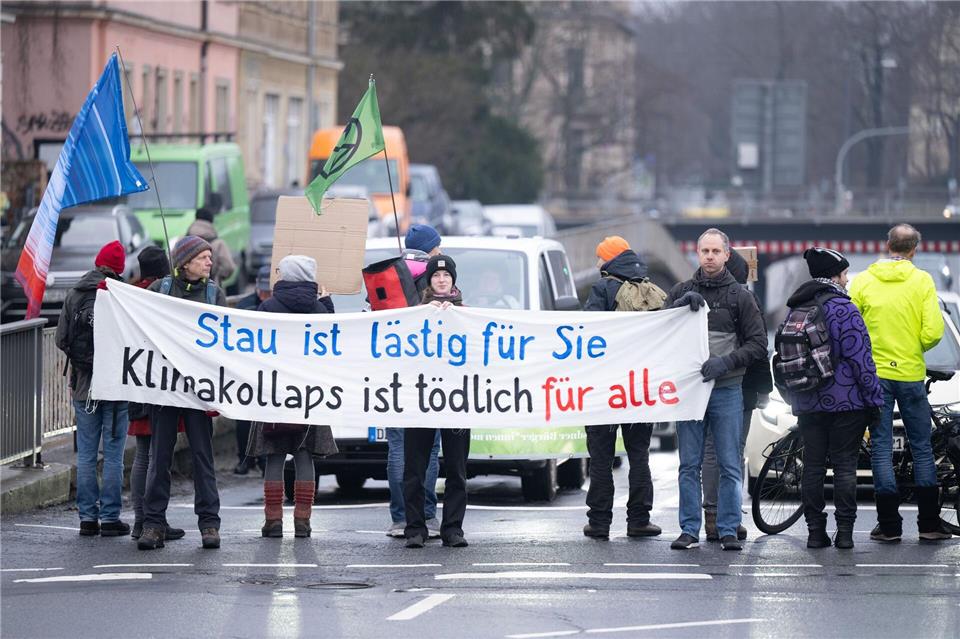 Klima-Aktivsten haben bei einer Straßenblockade eine „Wärmewende“ in Dresden hin zu erneuerbaren Wärmequellen verlangt. Sebastian Kahnert/dpa