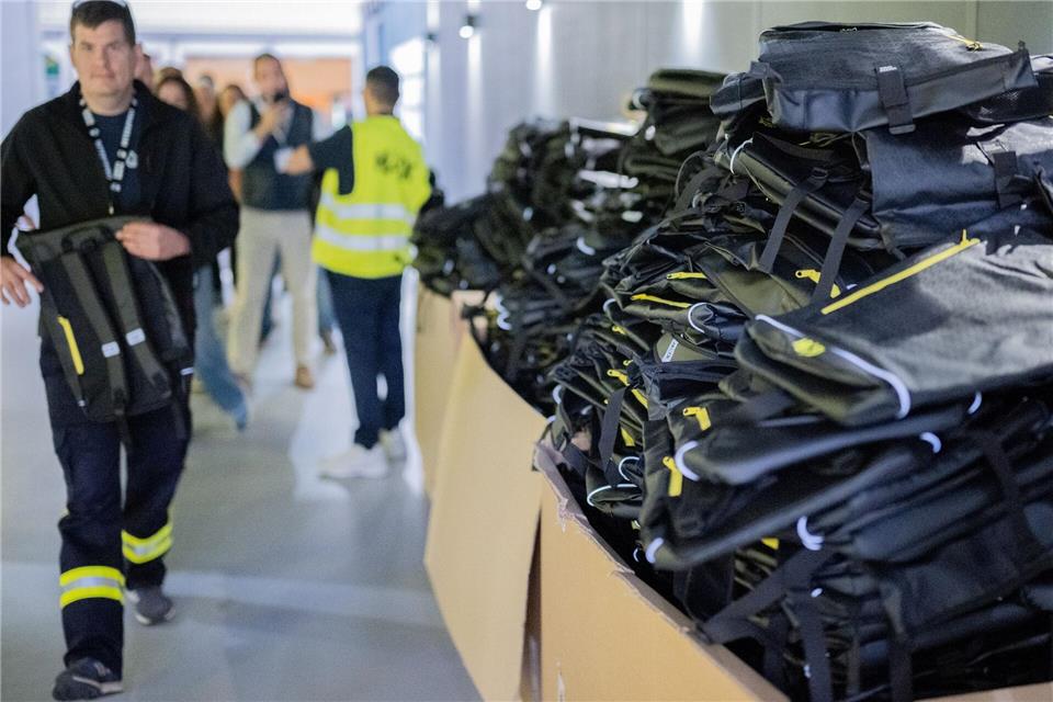 Kostenlose Rucksäcke liegen bei der Messe Interschutz an einem Stand. Julian Stratenschulte/dpa