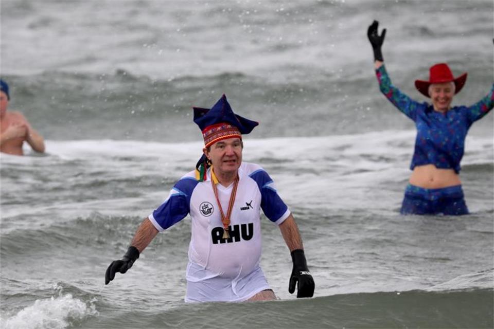 Lockdown-Trend Eisbaden: Heilsversprechen oder Risiko? Kostüme und lustige Kopfbedeckungen gehören in Warnemünde dazu zum Eisbaden. Foto: Bernd Wüstneck/dpa-Zentralbild/dpa