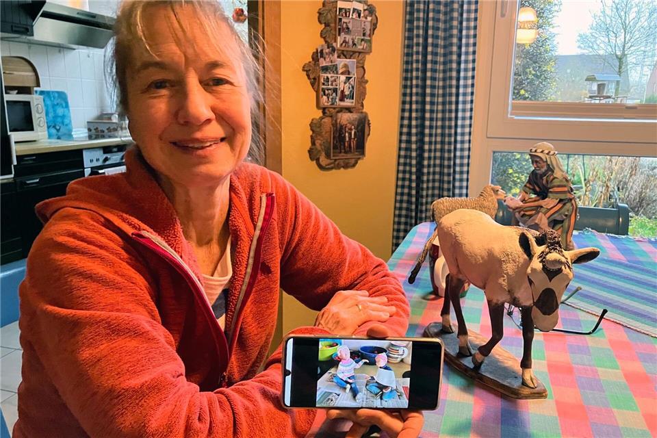 Krippenkünstlerin Annette Hiemenz sitzt an ihrer „Werkbank“, dem Küchentisch, und präsentiert einige ihrer jüngsten Krippenfiguren. Auf dem Mobiltelefon zeigt sie ein Foto der noch unfertigen Kinderfiguren, die Bestandteil ihres Exponates für die 85. Telgter Krippenkunst-Ausstellung sind.Volker Danisch/dpa