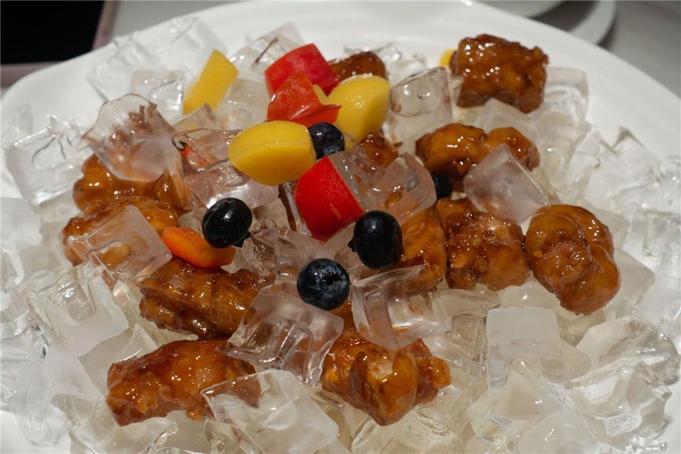 Kulinarische Überraschung in Shanghai: knuspriges Schweinefleisch süß-sauer mit Obststückchen in einer Schale aus Eiswürfeln.Andreas Drouve/dpa-tmn