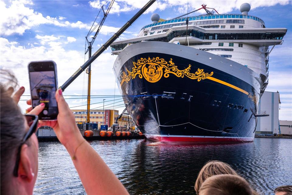 Kurz vor dem Verlassen der Werft in Wismar ist das Kreuzfahrtschiff „Disney Adventure“ beliebtes Fotomotiv für Touristen. Jens Büttner/dpa