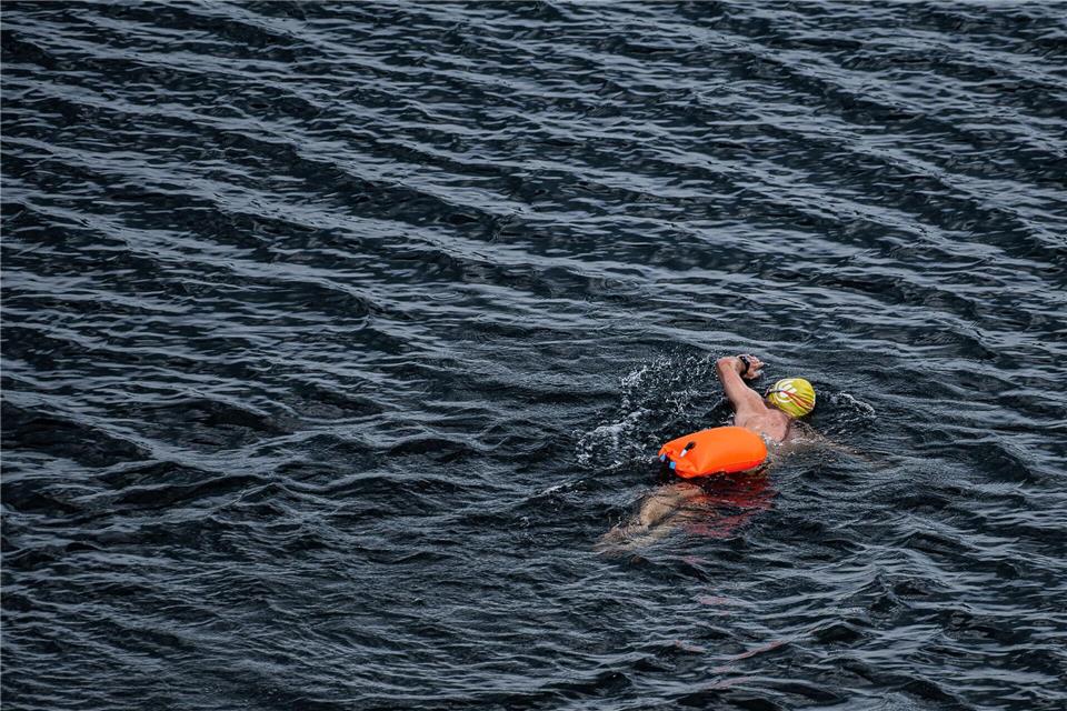 Leuchtend orange, pink oder gelb zieht sie hinter Schwimmern durchs Wasser: die Schwimmboje, befestigt über einen Gürtel. (Symbolbild)Swen Pförtner/dpa