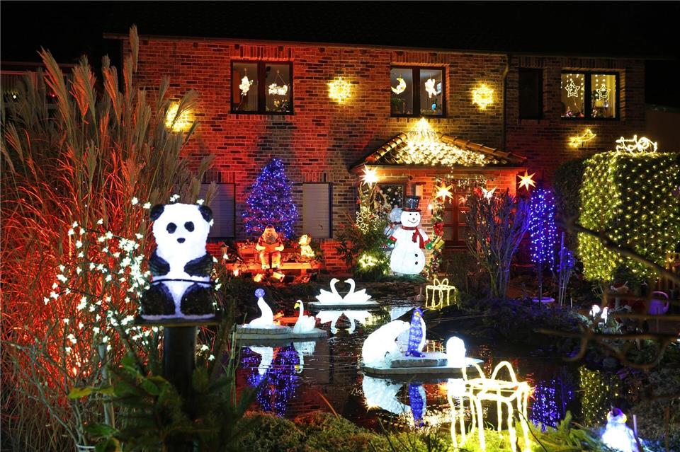 Leuchtende Figuren stehen im Vorgarten umgeben von zahlreichen weiteren Lichtern, die das Weihnachtshaus der Familie Lange erstrahlen lassen. Das Haus wird zur Adventszeit traditionell mit tausenden bunten Lichtern geschmückt.Matthias Bein/dpa