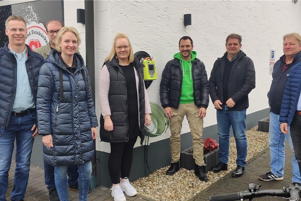 Ließen sich von Rainer Nawroth (2. v. re.) von der Firma 1A Medizintechnik aus Bocholt die Funktionsweise des neuen Defibrillators zeigen, der seit Ende April am Gebäude der Bäckerei Späker in Burlo hängt (v. li.): Reinhold Kuhlmann (Agri V Raiffeisen eG), Christian Ehling (Instrumentalgruppe der KLJB Borkenwirthe e.V), Stephanie Elfering (Agri V Raiffeisen eG), Christine Rottstegge (Werbekreis Burlo-Borkenwirthe e. V.), Julian Späker (Bäckerei Späker), Martin Dahlhaus (Stadt Borken) und Holger Wüstnienhaus (Sprecher der Dorfvertreterversammlung).
