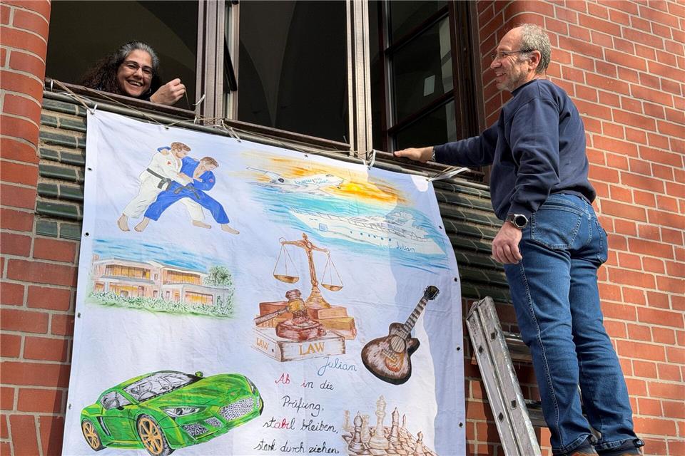 Lorans (l) und Marmik Yedgarian hängen ein Abiturplakat für die Abschlussprüfung ihres 19-jährigen Sohnes Julian in Wiesbaden auf.Jens Albes/dpa