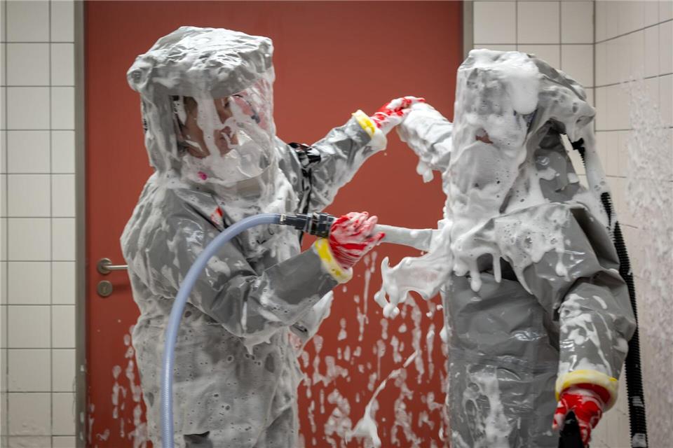 Louise Götze (l) und Ursula Pfitzner, Intensivpflegerinnen und Koordinatorinnen auf der Sonderisolierstation der Charité, desinfizieren sich während eines Pressetermins nach der Rückkehr aus dem Patientenzimmer in der Schleuse mit einer Schaumlösung.Soeren Stache/dpa