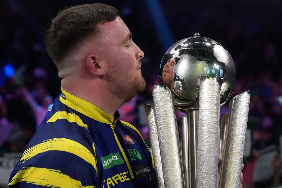 Luke Littler küsst die Trophäe nach seinem Sieg im Endspiel der Darts-WM.Dave Shopland/AP/dpa