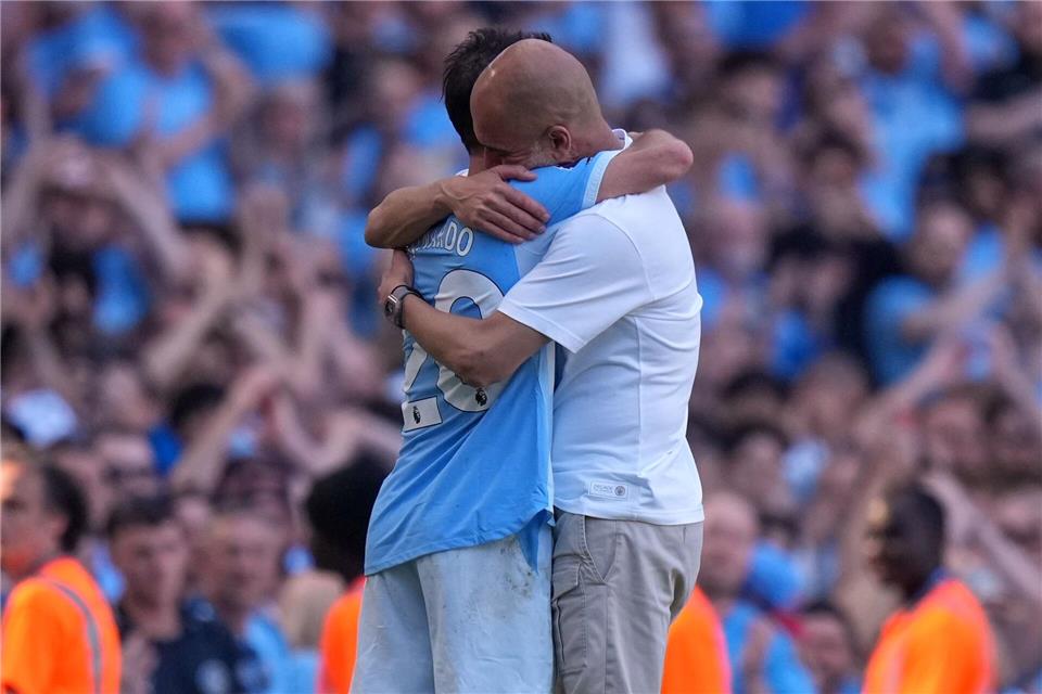 Manchester Citys Trainer Pep Guardiola (r) umarmt Bernardo Silva. Für beide war es das letzte City-Spiel.Alastair Grant/AP/dpa
