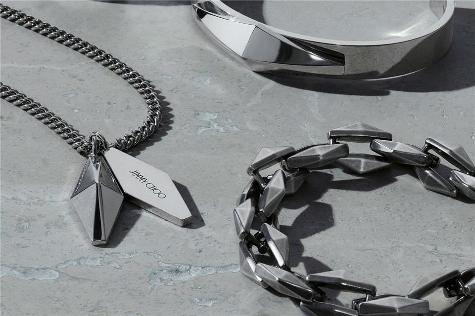 Mann trägt jetzt Kette - oder anderen Schmuck. In diesem Beispiel zu sehen: Stücke von Jimmy Choo (Kette ca. 340 Euro, Ring ca. 290 Euro, Armband oben ca. 315 Euro, Armband unten ca. 400 Euro).Jimmy Choo/dpa-tmn