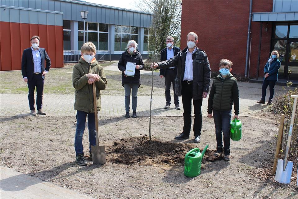 Manuel (links) und sein Mitschüler Pius haben den Baum mit der Hilfe von Martin Hillenbrand (rechts) gepflanzt.